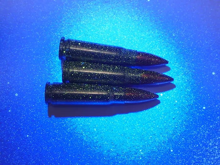 Photo of bullets covered in SmartWater fluorescing under UV light.